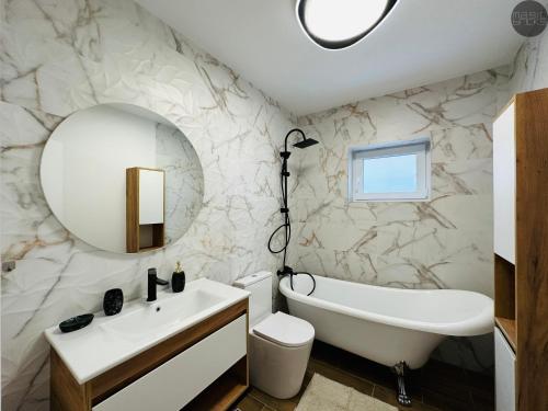 札勒乌magic bricks的浴室设有白色浴缸、水槽和镜子