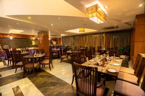 达卡孟加拉金丝雀公园酒店的一间在房间内配有桌椅的餐厅