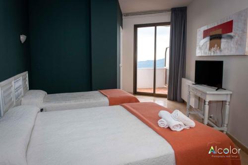 布鲁奇Hotel Bruc的一间卧室设有两张床、一台电视和一扇窗户。