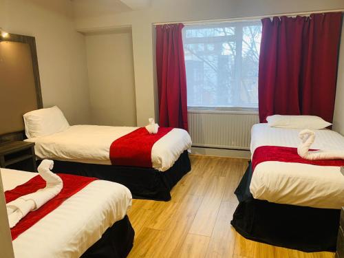 伦敦百合酒店的带三张床和窗户的客房