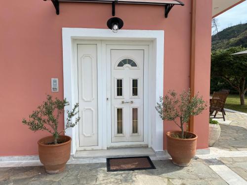 奥林匹亚Villa Aris的粉红色房子的白色门,两棵植物