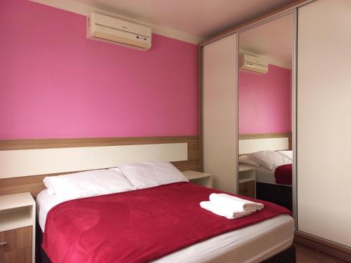 弗洛里亚诺波利斯Residencial Nicole的一间卧室设有粉红色的墙壁和一张带红色毯子的床。