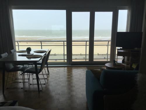 奥斯坦德Royal Zeezicht Oostende的一间带桌子的客厅,享有海滩美景