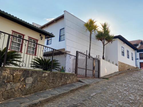 卡塔斯阿塔斯Casa no Centro Histórico de Catas Altas的一条棕榈树的白色房子,毗邻街道