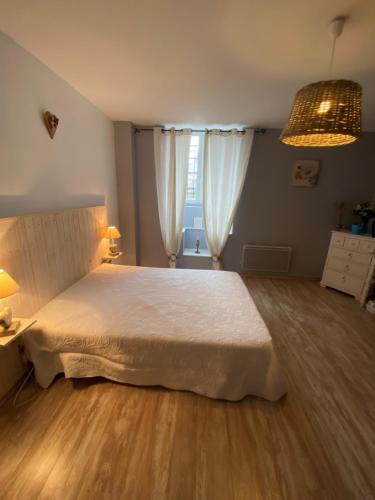 拉卡努尔格La Glycine的卧室配有一张白色大床,铺有木地板