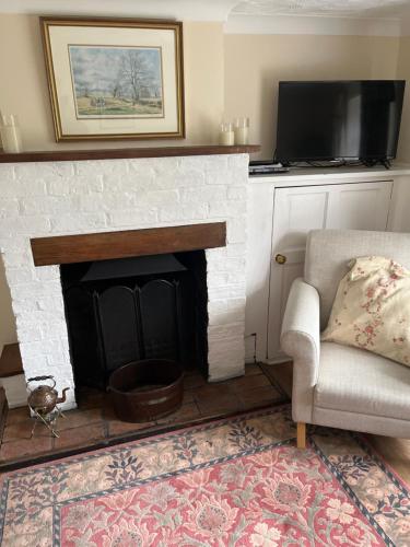 WhittleseyField Cottage的客厅设有壁炉、椅子和电视