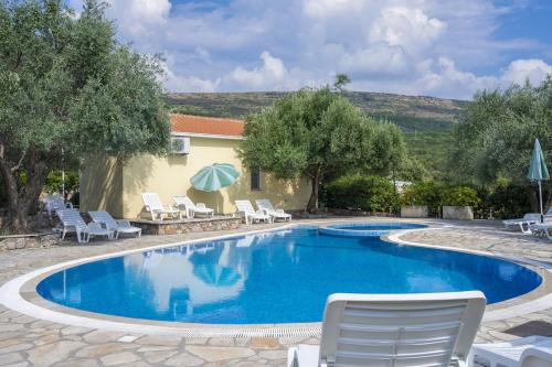 比戈沃Villa Thetis的房屋旁的游泳池配有椅子和遮阳伞