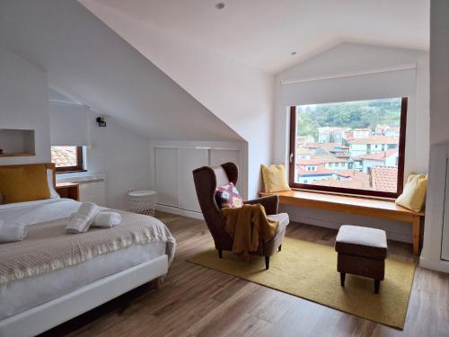 库迪列罗Apartamentos la Garita - Casa Miro y Marianita - Cudillero的卧室配有床、椅子和窗户。