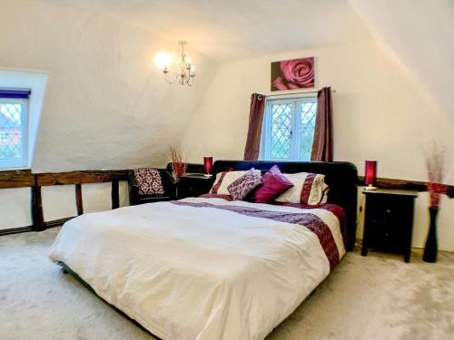 斯托马基特Laburnham Cottage的一间卧室配有一张大床和一个吊灯。