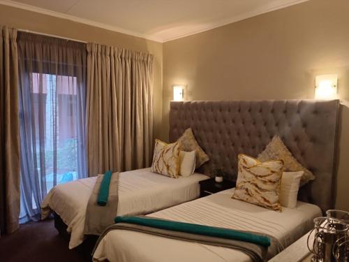 布隆方丹Apartment A8 inside Bains Lodge的酒店客房设有两张床和窗户。