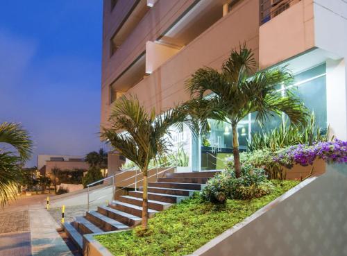 巴兰基亚Atlantis Suites Bquilla -Apartamento Moderno-2-BD的前面有楼梯和棕榈树的建筑