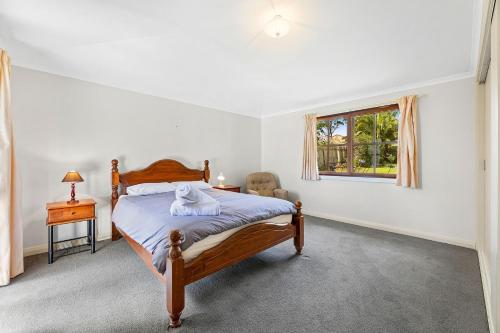 纳鲁马12 Bluewater Drive Narooma的卧室配有床、椅子和窗户。