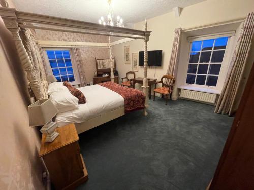 波塔费里The Portaferry Hotel的一间卧室配有一张床、一张书桌和两个窗户。