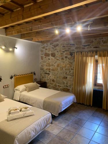 Villar de CiervoHabitaciones Rurales La Vertedera I的一间卧室设有两张床和石墙