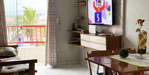 圣贝尔纳多-杜坎普Apartamento Pé na Areia的客厅配有桌子,墙上配有电视