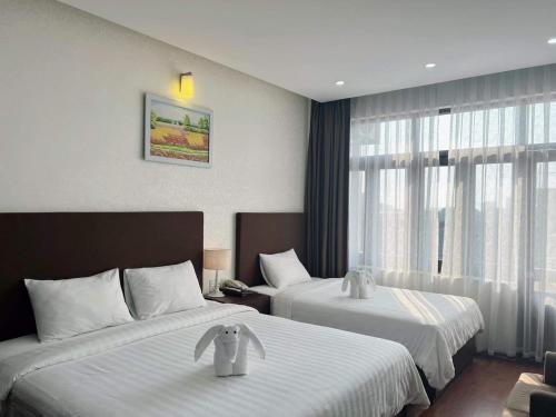 河静Bình Minh Hotel的酒店客房设有两张床和窗户。