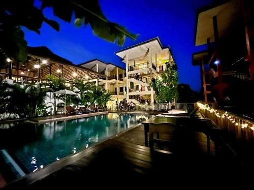 华欣Rainforest Huahin Village Hotel的一座游泳池,在晚上在建筑物前