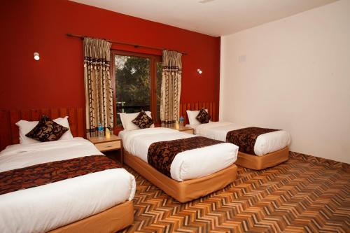 奇旺Sauraha Holiday Home Riverside的酒店客房,设有三张床和红色的墙壁