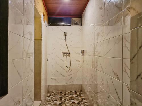 乌布Sanga Suites的浴室设有白色大理石瓷砖和淋浴。