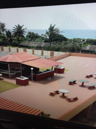 德班Amanzimtoti Beachfront Holiday Apartment , Flat No 23, Ezulweni的享有带屋顶桌子的庭院的景色。