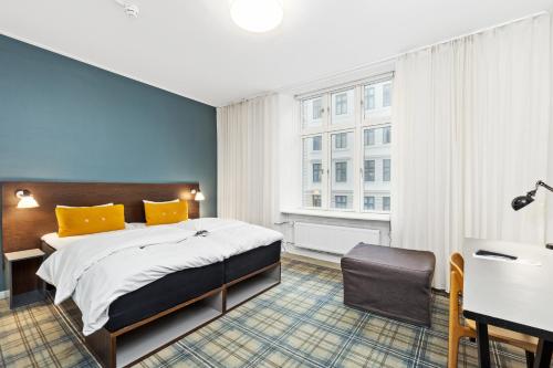 哥本哈根易卜生酒店的一间卧室配有一张床、一张书桌和一个窗户。