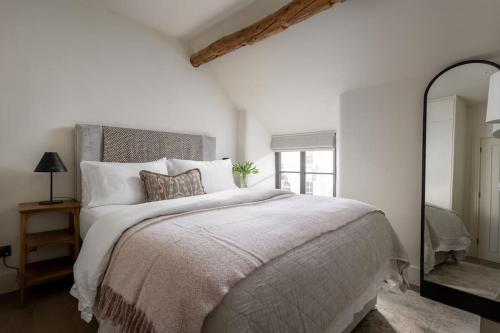 斯托昂泽沃尔德Whitsun Cottage的白色卧室设有一张大床和镜子