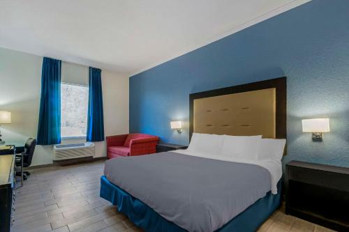 卫斯理堂韦斯利礼拜堂罗德威旅馆的一间卧室配有一张大床和一张红色椅子