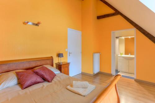 塔登Tour des Alleux - Maison de maître pour 6的一间卧室拥有橙色的墙壁,配有一张带枕头的床。
