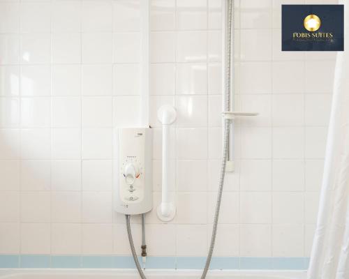 达格纳姆Fobis Suites Short Lets for 3 Bed Family Group Contractors Dagenham的浴室设有白色瓷砖墙和淋浴。