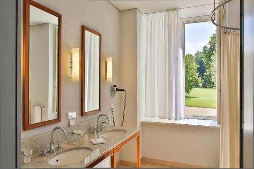 新哈登贝格新哈登贝格施洛斯酒店的一间带两个盥洗盆的浴室和一个大窗户