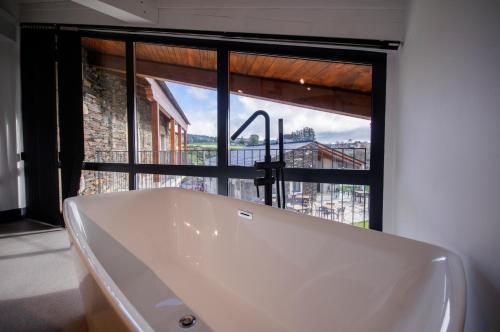 FriolHotel Rural O Cruce do Burgo的带浴缸的浴室和大窗户