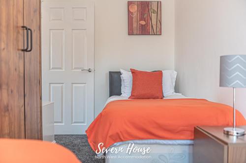 利Severn Street House Serviced Accommodation的一间卧室配有一张带橙色毯子的床