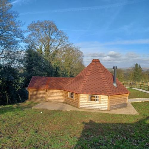 Rushton SpencerAntler Lodge的田野上带红色屋顶的小房子