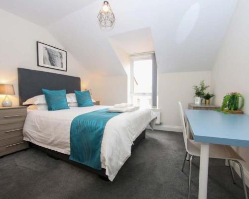 斯旺西Luxe Living Guest House-Sleeps 6 -Family Friendly-Private Parking-Wifi-City-Beach的一间卧室配有一张大床和一张蓝色的书桌