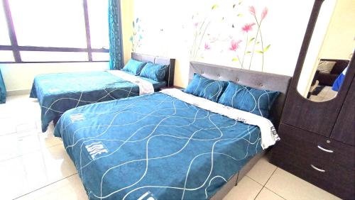 巴特沃思Mevin Woodsbury Suite Butterworth Penang的配有两张蓝色床单和镜子的客房内的床铺
