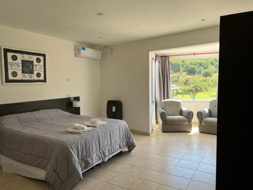 梅洛La Herradura Village的一间卧室配有一张床、两把椅子和一个窗户
