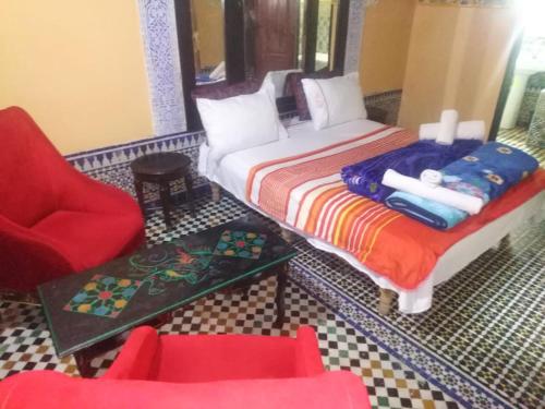 非斯riad zahra的一间卧室配有一张床、一把椅子和一张桌子