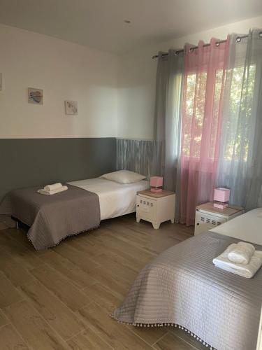 博尼法乔A Santa Trinita的一间设有两张床和两张桌子及窗帘的房间