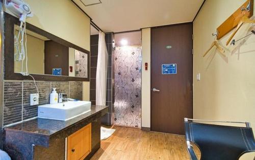 群山市Chakan Hotel的一间带水槽、镜子和淋浴的浴室