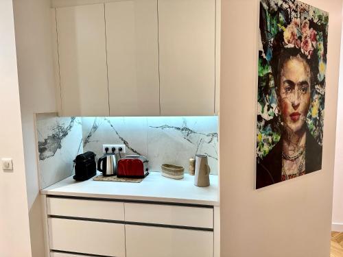 兰斯Bel Appartement avec parking au coeur de Reims的厨房配有白色橱柜,墙上挂有绘画作品