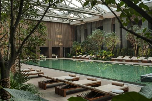北京北京瑰丽酒店的一座带躺椅的建筑内的游泳池