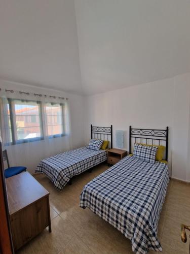 塔拉哈勒赫TaraVilla的一间卧室设有两张床、一张桌子和窗户。