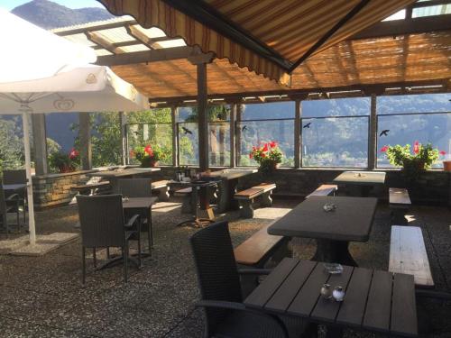 加维科利亚诺Hotel Bellavista Cavigliano的餐厅配有桌椅,位于山脉的背景中