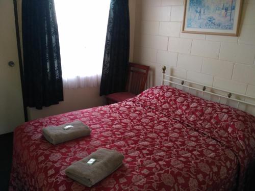 莱文Amble Inn Motel的一间卧室配有红色的床和2条毛巾