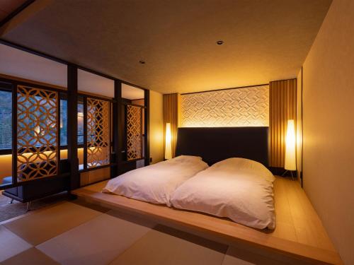 砺波市三乐园日式旅馆的一间卧室配有白色床单和灯。