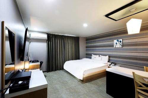 全州市怀特旅行酒店的酒店客房配有一张床、一张书桌和一台电视。