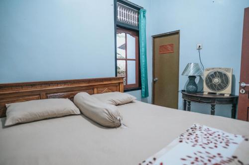 外南梦Agus Hidden Homestay - Banjar Sweet Village的一间卧室配有一张带枕头的床和风扇