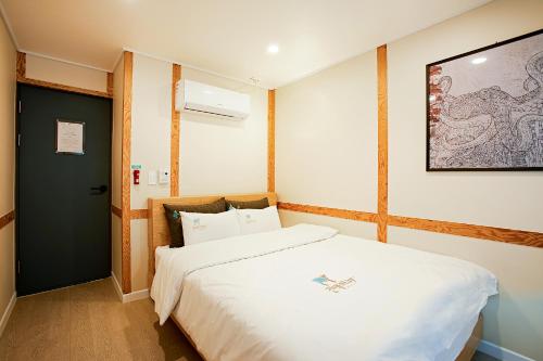 木浦市Geonmaek Stay的卧室配有白色的床和墙上的绘画作品