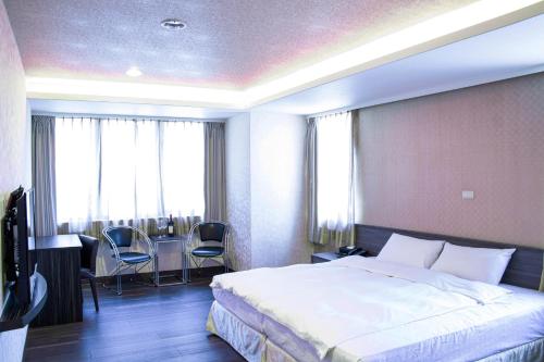 埔里埔里西站旅馆的酒店客房带一张床、一张桌子和椅子