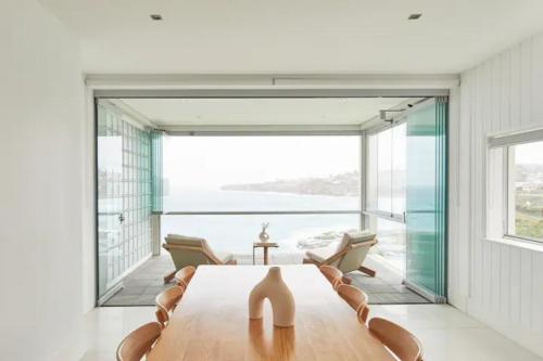 悉尼Oceanfront Tamarama Apartment: Best View in Sydney的一间带桌子和大窗户的用餐室